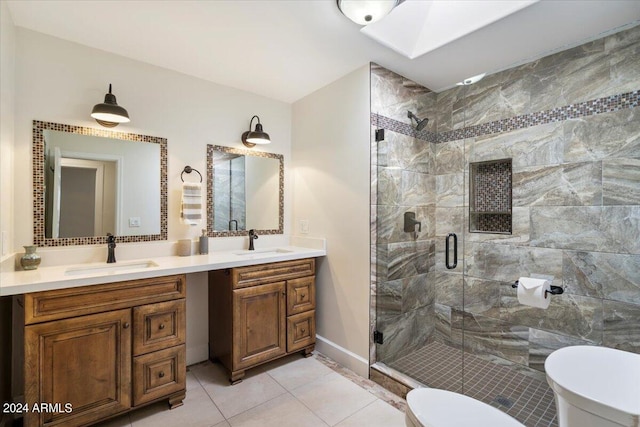 bathroom with a skylight, vanity, tile patterned floors, toilet, and a shower with door