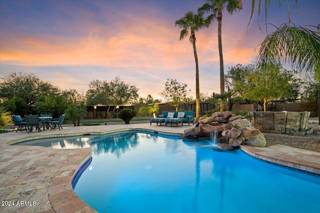 pool at dusk with a patio and an outdoor living space