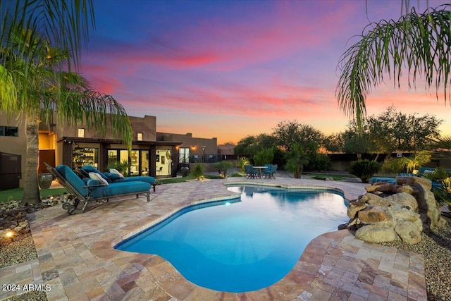 pool at dusk with a patio area