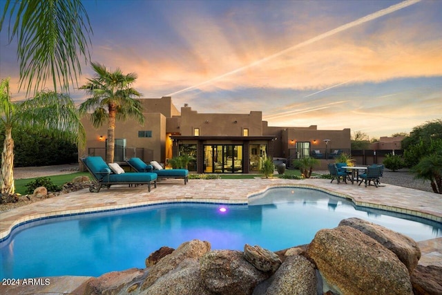 pool at dusk with a patio area