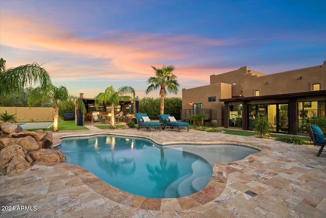 pool at dusk with a patio area