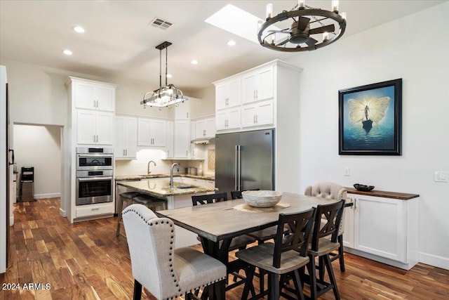 dining room featuring a skylight, dark wood-type flooring, and sink