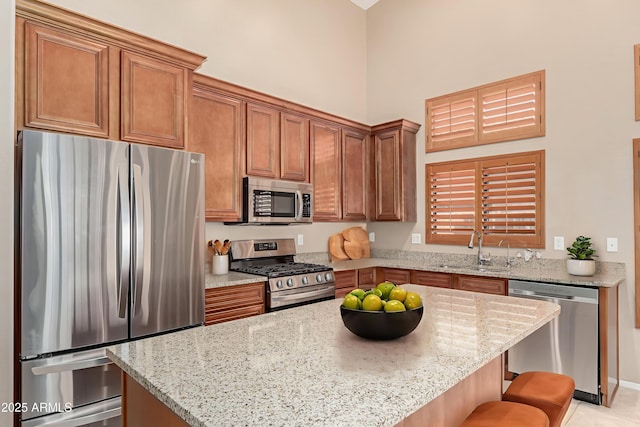 6936 E Snowdon St, Mesa, AZ 85207 - kitchen featuring stainless steel appliances, light stone countertops, brown cabinets, a kitchen breakfast bar, and a high ceiling