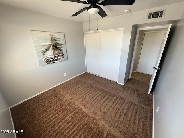 unfurnished bedroom featuring ceiling fan, dark carpet, and a closet