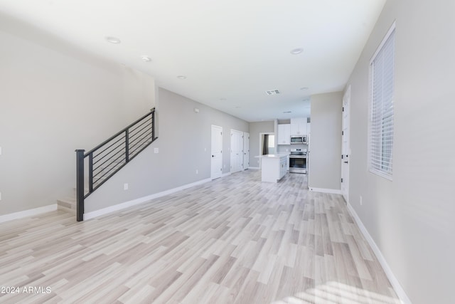 unfurnished living room featuring visible vents, recessed lighting, light wood-style floors, baseboards, and stairs