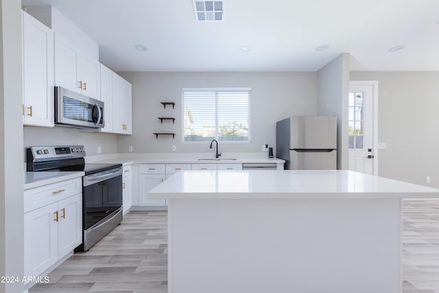 kitchen featuring visible vents, a sink, a kitchen island, appliances with stainless steel finishes, and light countertops