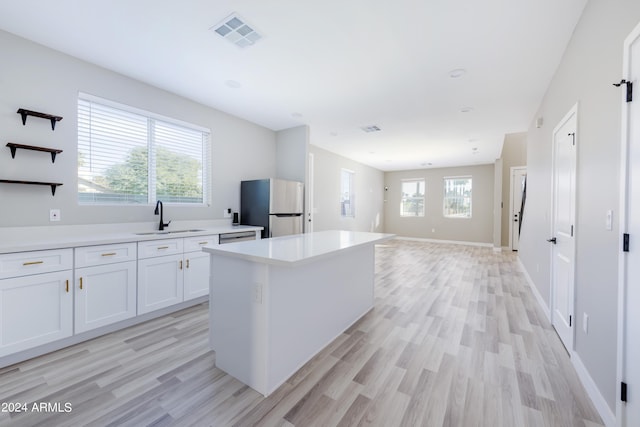 kitchen with visible vents, light wood finished floors, freestanding refrigerator, a sink, and light countertops