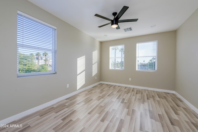 unfurnished room with visible vents, plenty of natural light, light wood-style flooring, and baseboards