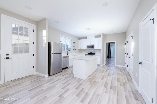 kitchen featuring a kitchen island, white cabinetry, appliances with stainless steel finishes, light countertops, and baseboards