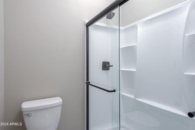 full bathroom featuring a stall shower and toilet