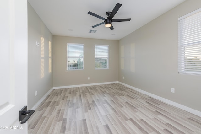 empty room featuring ceiling fan, a healthy amount of sunlight, visible vents, and baseboards