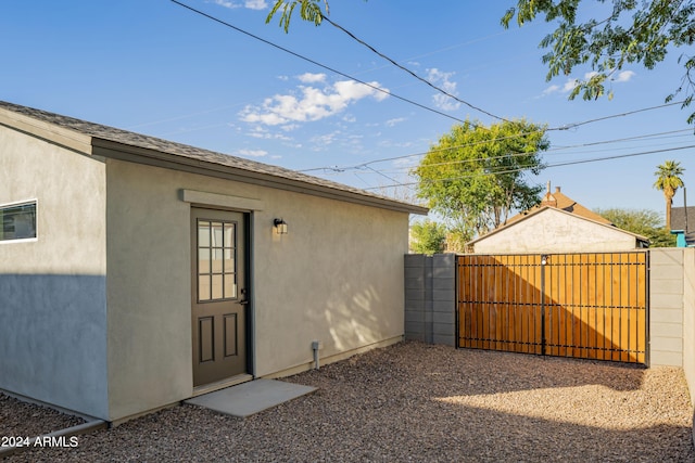 view of exterior entry featuring stucco siding, fence, and a gate