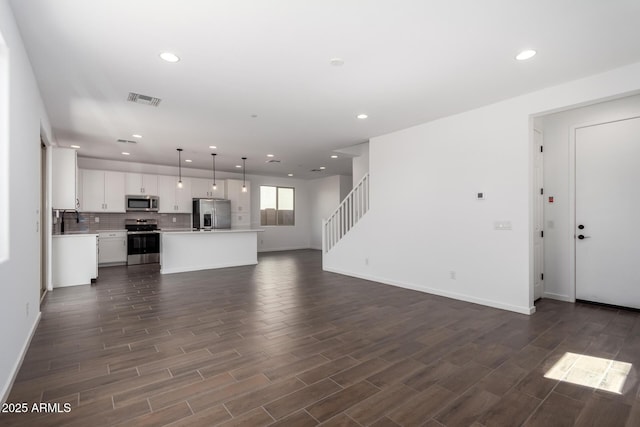 11627 W Green Dr, Youngtown, AZ 85363 - unfurnished living room with recessed lighting, dark wood-style flooring, stairway, baseboards, and a sink