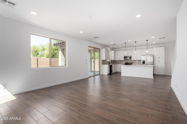 11627 W Green Dr, Youngtown, AZ 85363 - unfurnished living room with recessed lighting, baseboards, dark wood-type flooring, and a sink