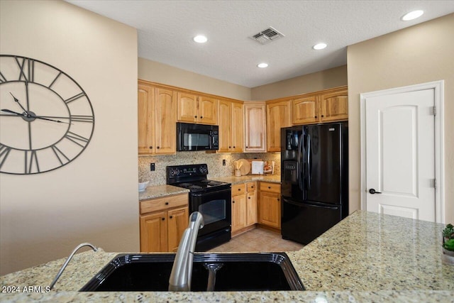 kitchen featuring backsplash, black appliances, sink, light stone countertops, and a textured ceiling