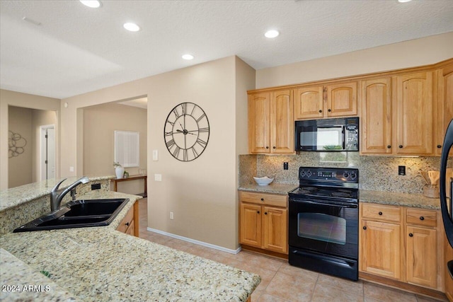 kitchen with backsplash, light stone countertops, sink, and black appliances