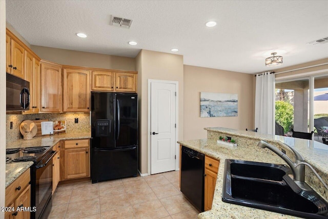 kitchen featuring decorative backsplash, light stone counters, sink, and black appliances