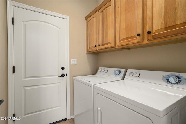 washroom with washer and dryer and cabinets