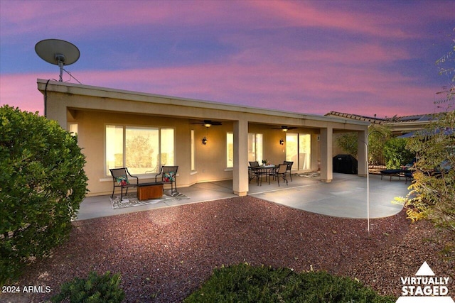 back house at dusk featuring ceiling fan and a patio