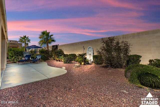 yard at dusk featuring a patio area