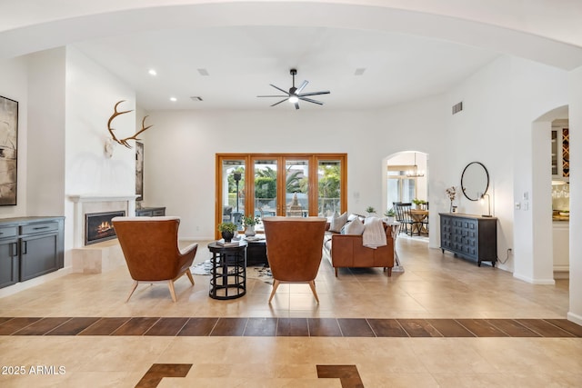 living room with a high ceiling, a healthy amount of sunlight, and ceiling fan with notable chandelier