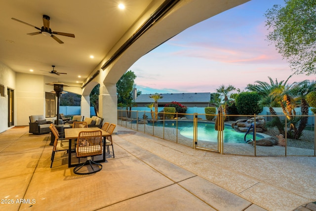 patio terrace at dusk with a fenced in pool, outdoor lounge area, and ceiling fan