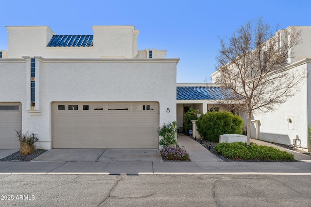 multi unit property featuring a tiled roof, a garage, driveway, and stucco siding