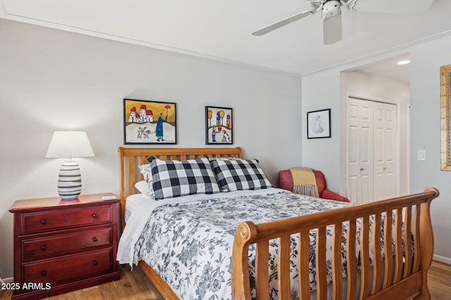 bedroom with a closet, ornamental molding, ceiling fan, and wood finished floors