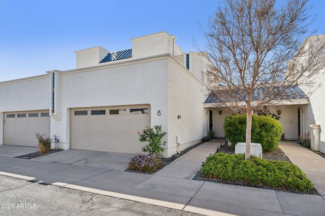 view of front of house with stucco siding, driveway, and an attached garage