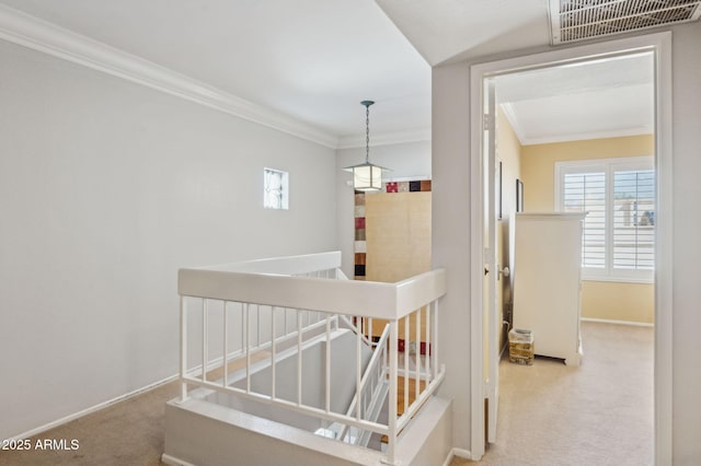 hall with visible vents, an upstairs landing, carpet, and ornamental molding