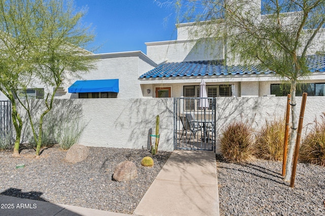 view of front of property with a fenced front yard, stucco siding, and a gate