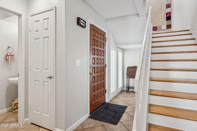 entrance foyer featuring baseboards, stairs, and tile patterned flooring