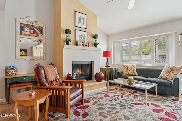 living room featuring tile patterned floors, a warm lit fireplace, ceiling fan, and vaulted ceiling