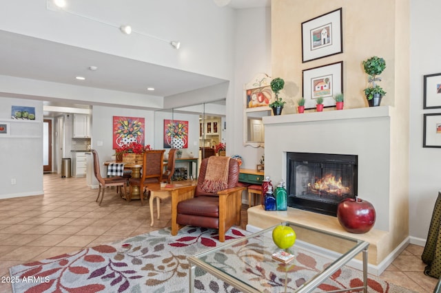 living room featuring a glass covered fireplace, tile patterned floors, a high ceiling, and baseboards