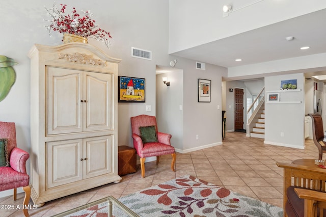 sitting room featuring light tile patterned floors, visible vents, and stairs