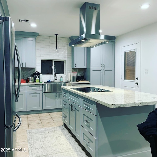 kitchen with island exhaust hood, tasteful backsplash, freestanding refrigerator, and a sink