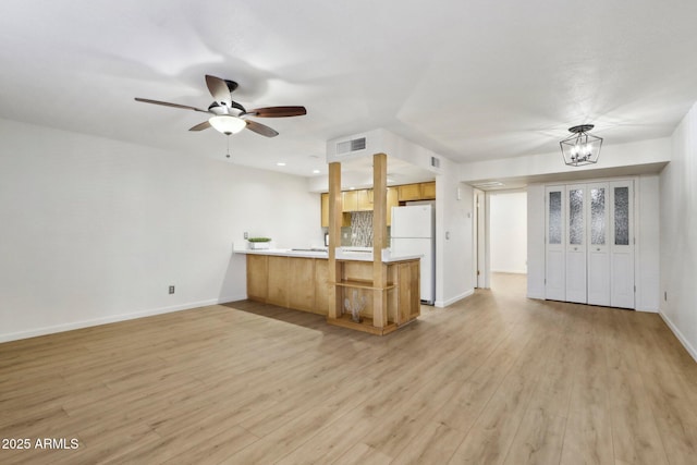 kitchen featuring a peninsula, visible vents, open floor plan, light wood-type flooring, and freestanding refrigerator