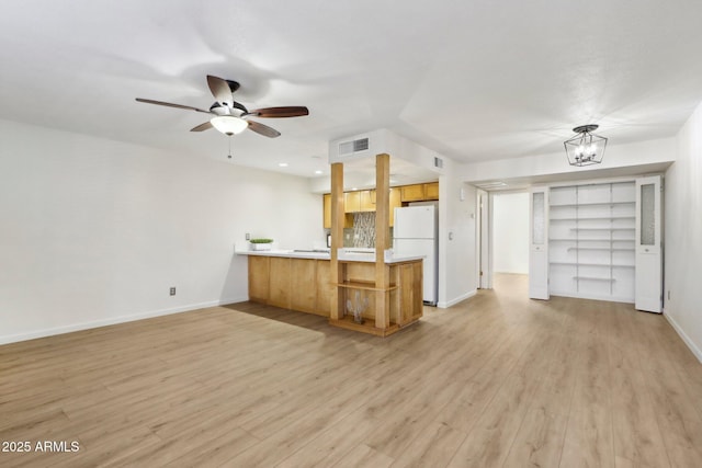 kitchen featuring visible vents, light wood-style flooring, freestanding refrigerator, open floor plan, and a peninsula