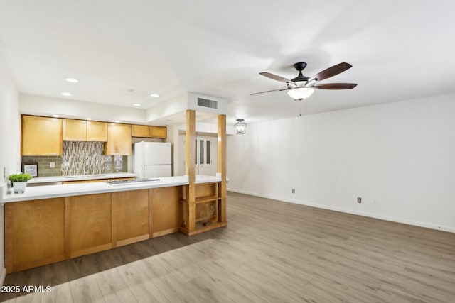 kitchen featuring tasteful backsplash, visible vents, wood finished floors, freestanding refrigerator, and a peninsula