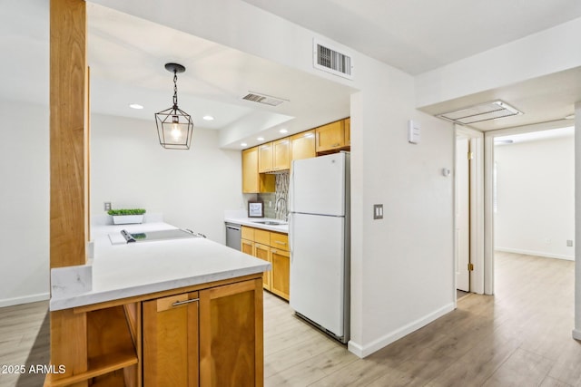 kitchen featuring light wood-style floors, freestanding refrigerator, visible vents, and a sink