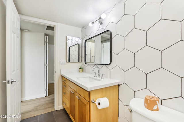 half bath with tasteful backsplash, visible vents, toilet, vanity, and tile walls