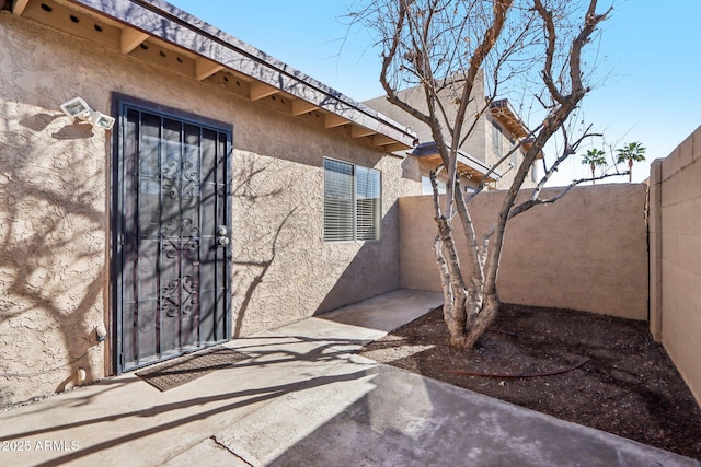 entrance to property with fence and stucco siding