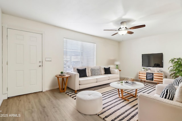 living area with ceiling fan, light wood finished floors, and baseboards