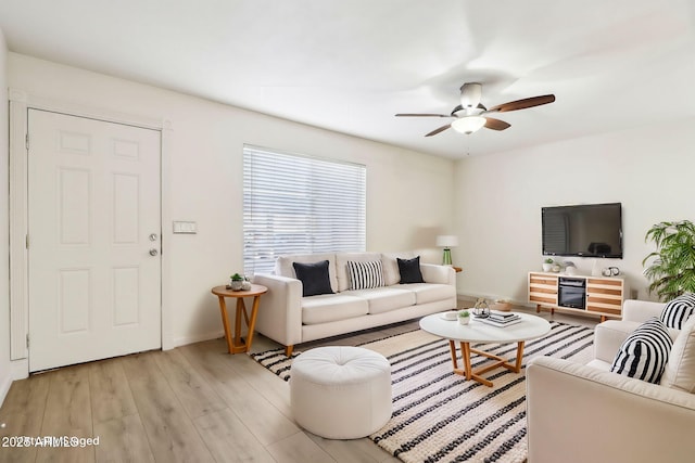 living area with light wood-style floors, ceiling fan, and baseboards