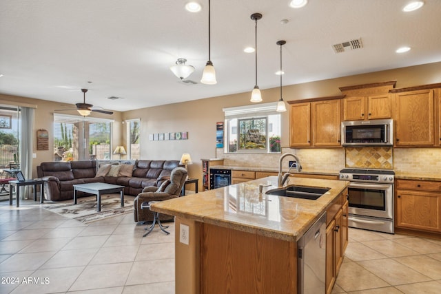 kitchen with an island with sink, stainless steel appliances, plenty of natural light, and sink