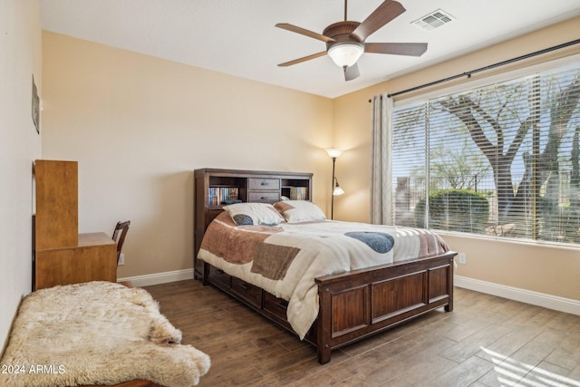 bedroom featuring ceiling fan, dark hardwood / wood-style flooring, and multiple windows