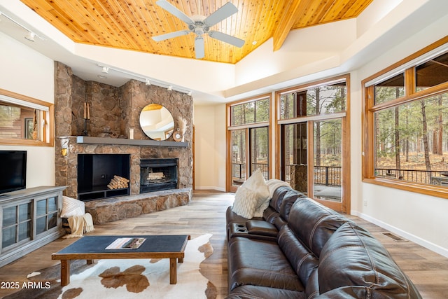 living area featuring a tray ceiling, a fireplace, wood finished floors, wooden ceiling, and baseboards