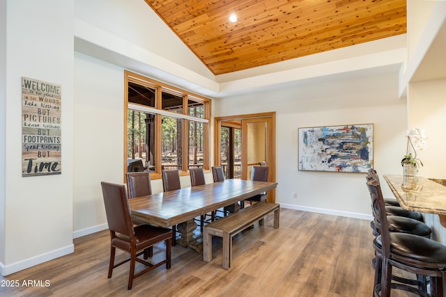 dining space with high vaulted ceiling, wooden ceiling, wood finished floors, and baseboards