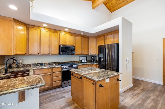 kitchen featuring appliances with stainless steel finishes, a sink, a kitchen island, dark stone countertops, and light wood-type flooring