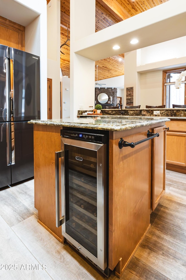 kitchen featuring stone countertops, wine cooler, light wood-style flooring, and freestanding refrigerator